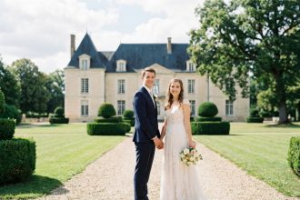 Couple souriant en mariage devant un château élégant